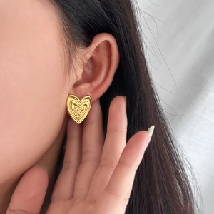 Close-up of woman wearing vintage gold pleated heart earrings in polished stainless steel