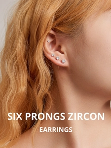 Close-up of four graduated sizes of six-prong zircon earrings worn on a model's ear