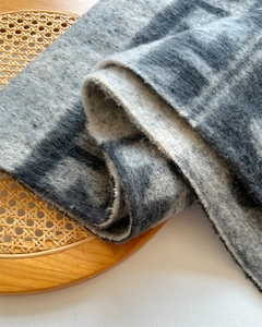 Close-up of soft cashmere-like gray polka dot fabric texture draped on a rattan chair