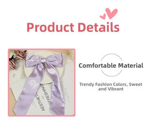 Detail of purple satin bow hair clip featuring soft fabric texture and long streamers