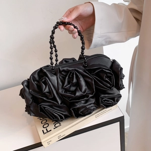 Detail of elegant black silk evening bag featuring 3D rose flowers and beaded handle