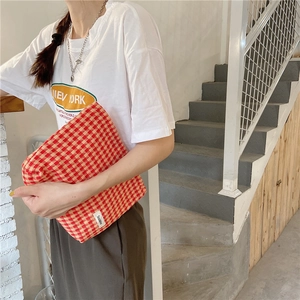 Detalle del neceser jacquard de cuadros rojos y amarillos con cremallera y etiqueta tejida