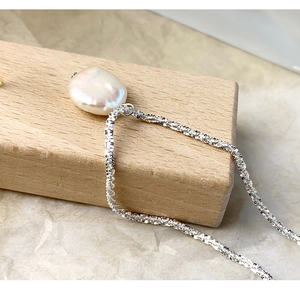 Close-up of a natural white baroque pearl pendant on a shimmering S925 silver chain