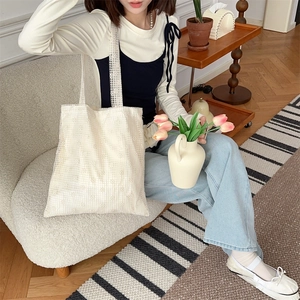 Detailed close-up of cream lace mesh tote bag with floral patterns on casual outfit