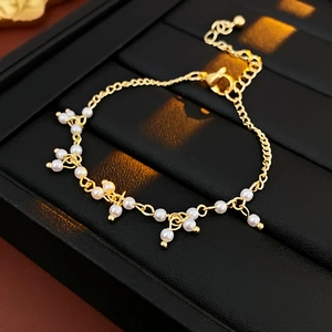 Dettaglio del bracciale con perle dorate, ciondolo a cuore e catena regolabile