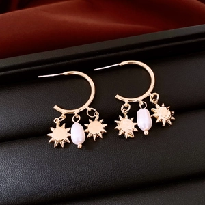 Detail of gold sun pendants and pearl earrings on black leather jewelry box background