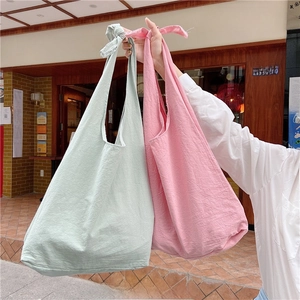 Detail of knotted handle straps and natural cotton linen texture on shoulder bags