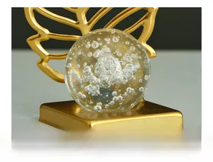 Close-up of golden leaf metal base holding a crystal ball with internal bubbles