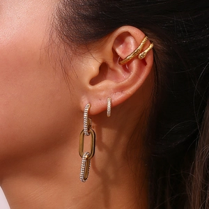 Close-up of golden textured ear cuff and pavé zircon hoop earrings on model's ear