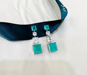 Macro detail of emerald-cut green crystal earrings with cubic zirconia on silver metal