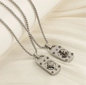 Détail macro de pendentifs boussole et ancre nautiques sur fond de tissu blanc
