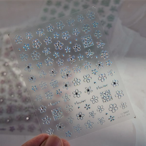 Vue macro détaillée de stickers à ongles holographiques aux motifs fleurs et cristal