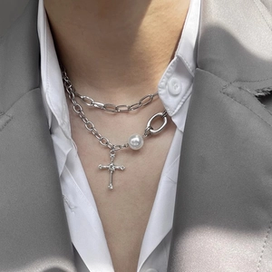 Close-up of double-layered silver necklace with white pearl and diamond cross pendants