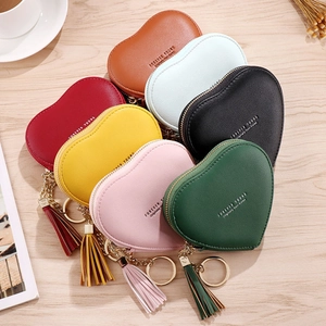 Flat lay of colorful heart-shaped mini wallets with gold zippers and tassels on wood