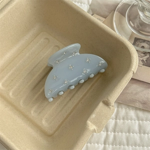 Detail of light blue acrylic hair claw with star rhinestones in a minimalist eco box