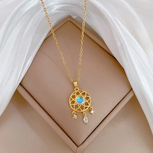 Gold dreamcatcher necklace with blue gemstone and sparkling crystals on silk background