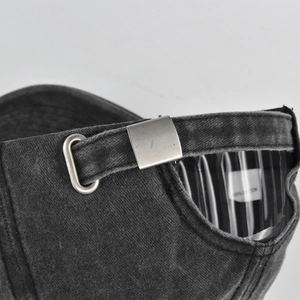 Detail of vintage baseball cap metal buckle and 100% cotton tag on washed dark grey fabric
