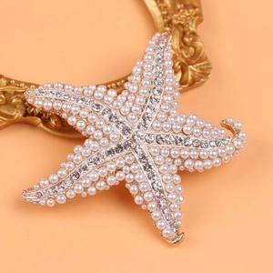 Starfish brooch with pearls and rhinestones on peach background with gold frame