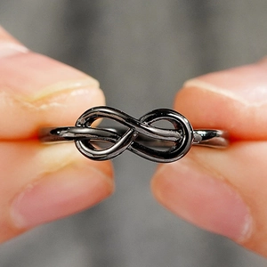 Macrodetail van een minimalistische zwarte infinity metalen ring met een glanzende finish