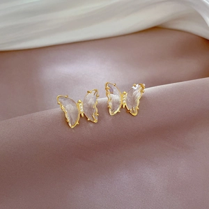 Macro detail of gold butterfly earrings with crystal stones on silk fabric