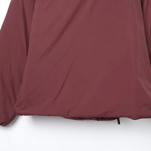 Detalle de chaqueta cortavientos burdeos con cremallera y dobladillo elástico