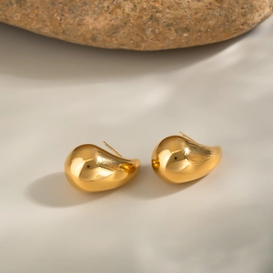 Detailed close-up of gold teardrop earrings on a stone background in 18k gold plating