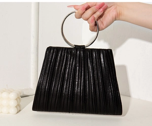 Detail of black pleated clutch featuring a circular metallic handle for evening elegance
