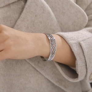 Silver stainless steel open cuff bracelet with cutout Celtic knot pattern on wrist