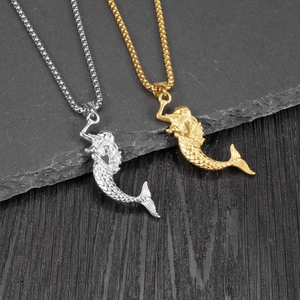 Detailed view of hip hop mermaid pendants in silver and gold on a dark stone background