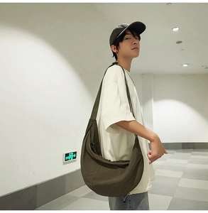 Détail du sac bandoulière en nylon vert armée porté par un mannequin homme