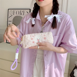 Quilted beige pencil case with cute dog embroidery and a purple carry handle strap