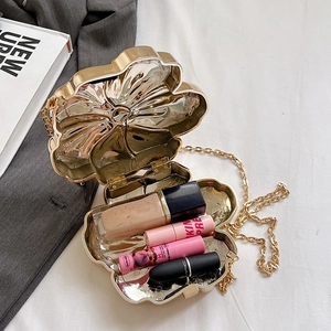 Detailed interior view of a gold flower-shaped evening bag with chain and cosmetics