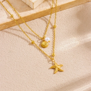 Double-layered gold starfish and shell pendant necklace with pearls on beige stone