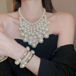 Detail of elegant layered white pearl necklace and gold metal accent bracelet on model