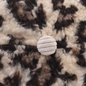 Macro shot of leopard print corduroy texture with central cream ribbed button detail