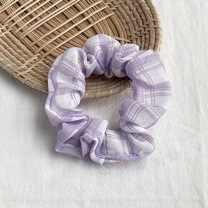 Detail of purple and white checkered fabric scrunchie resting on a rustic straw tray