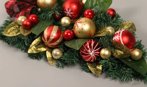 Close-up of artificial Christmas wreath with pine needles, red glitter balls, and plaid bow