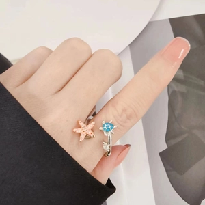 Silver open ring with a gold starfish and blue turtle design worn on a hand