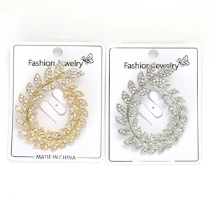Detailed view of olive leaf wreaths brooches in gold and silver with rhinestones