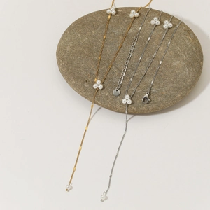 Elegant Y-shaped pearl necklace in gold and silver finish on a smooth stone