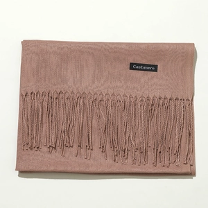 Detail shot of dusty pink scarf with fringe and black Cashmere fabric label tag