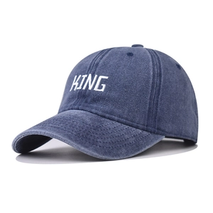 Detailed close-up of white KING embroidery on washed navy blue denim baseball cap