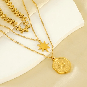 Dreilagige goldene Edelstahlkette mit Stern, Münze und Herzanhänger auf Seidenstoff