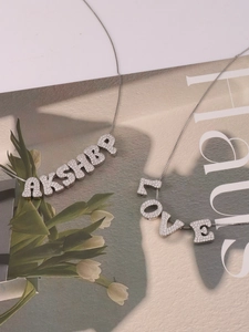 Detailed view of silver letter necklaces with sparkling zircons on a fashion magazine