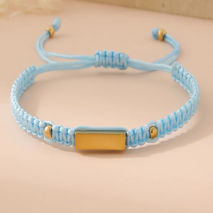 Detail of hand-woven light blue cord bracelet with a polished gold metal plate and beads