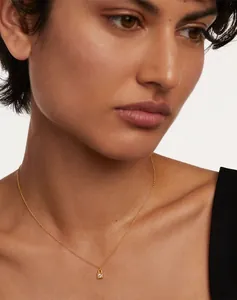 Close-up of a gold S925 silver necklace with a crystal lock pendant on a woman neck