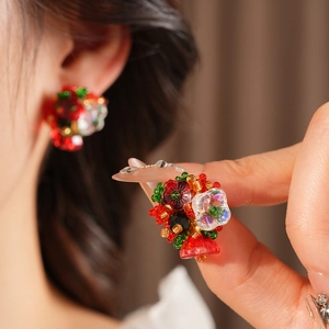 Macro view of handmade Christmas beaded floral stud earrings with red and green details