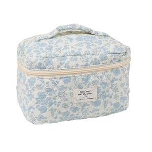 Quilted cotton makeup bag with blue floral pattern and top handle on white background