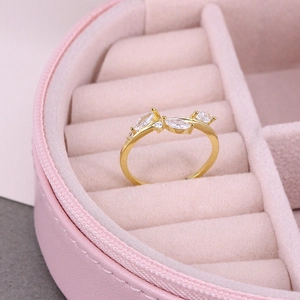 Close-up of golden leaf ring with zircon stones in a pink velvet jewelry case