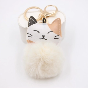 Detail of calico cat plush keychain with a soft faux fur pompom and gold metal clasp